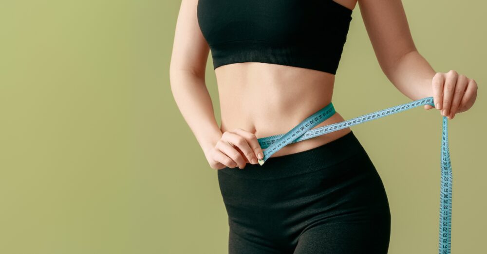 Woman measuring her slimmer waist